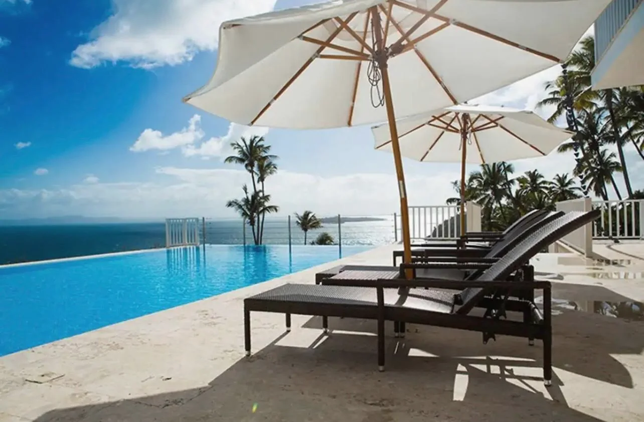 Infinity pool with parasols and loungers facing Samaná Bay